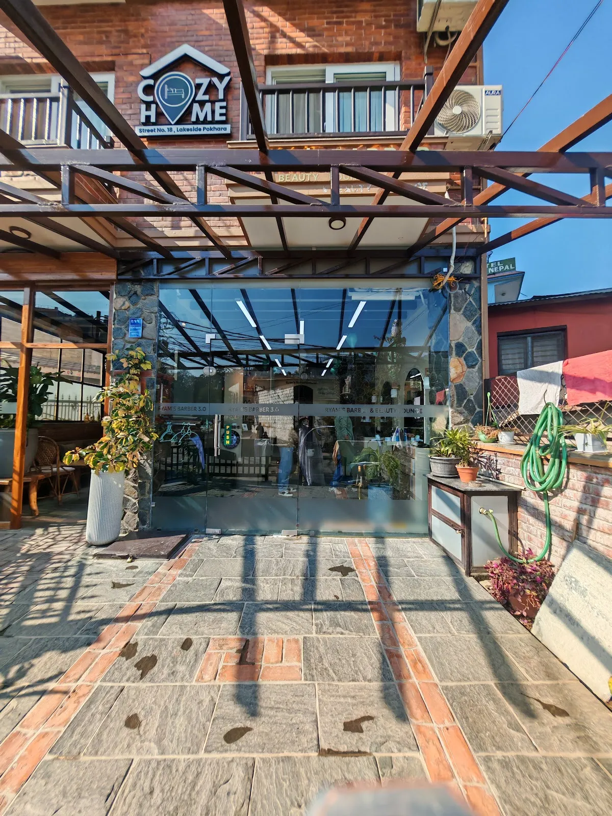Glass shopfront of Ryam's Barber on the ground floor of Cozy Home, Pokhara